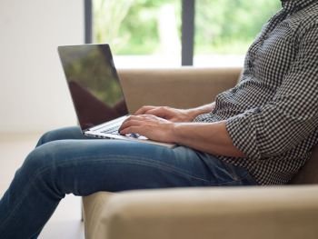 Young, handsome man using laptop sitting on sofa