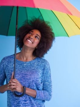 Portrait of young beautiful african american woman holding a colorful umbrella isolated on a Blue background