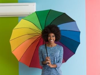 Portrait of young beautiful african american woman holding a colorful umbrella isolated on a Colorful background