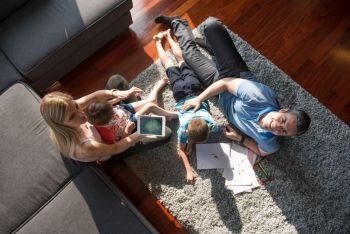 Happy Young Family Playing Together at home on the floor using a tablet and a children’s drawing set top view