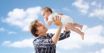 family, fatherhood and parenthood concept - happy smiling young father with little baby over blue sky and clouds background