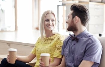business, startup, people and communication concept - happy man and woman drinking coffee and talking in office
