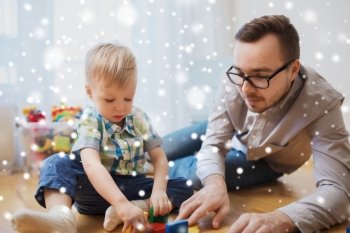 family, childhood, creativity, activity and people concept - happy father and little son playing with toy blocks at home over snow