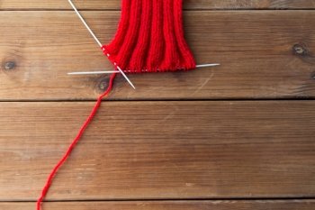 handicraft and needlework concept - hand-knitted item with knitting needles on wood. hand-knitted item with knitting needles on wood