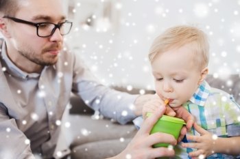 family, childhood, fatherhood, care and people concept - father helping little son with drinking from cup at home over snow