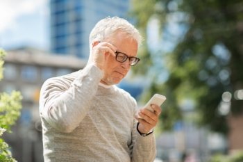 technology, people, lifestyle and communication concept - senior man texting message on smartphone in city