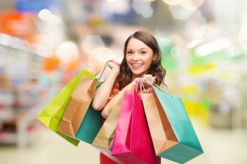 sale and people - smiling woman with colorful shopping bags over supermarket background. woman with shopping bags at store