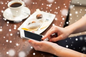 business, people, technology and lifestyle concept - close up of woman with smartphone, coffee and dessert over snow
