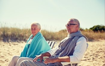 family, age, travel, tourism and people concept - happy senior couple resting in folding chairs on summer beach