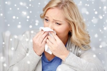 health care, flu, hygiene and people concept - ill woman blowing nose to paper napkin over snow