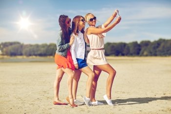 summer vacation, holidays, travel, technology and people concept- group of smiling young women taking selfie with smartphone on beach