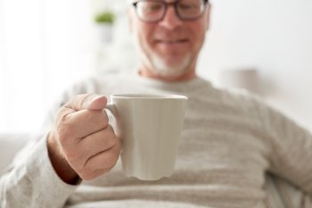 old age, drink and people concept - happy senior man with cup of tea or coffee at home