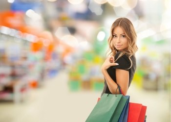 sale and people - woman with colorful shopping bags over supermarket background. woman with shopping bags at store or supermarket