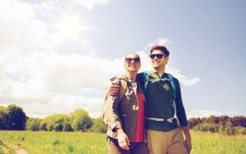 travel, hiking, backpacking, tourism and people concept - happy couple with backpacks hugging and walking outdoors