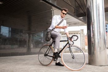lifestyle, transport, communication and people concept - young man with bicycle and smartphone on city street