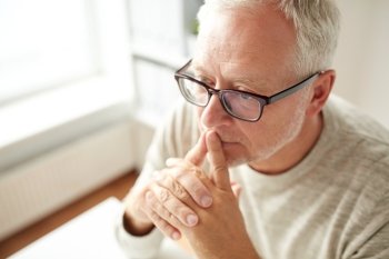 old age, problem and people concept - close up of senior man in glasses thinking