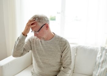 healthcare, pain, stress, age and people concept - senior man suffering from headache at home