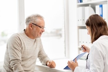 medicine, age, health care and people concept - senior man and doctor with clipboard meeting in medical office at hospital