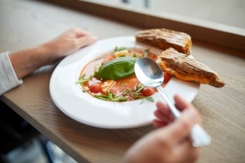 food, dinner, culinary and people concept - woman eating gazpacho soup with sandwich and spoon at restaurant