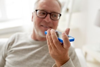 technology, people, lifestyle and communication concept - close up of happy senior man using voice command recorder or calling on smartphone at home