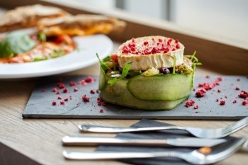 food, culinary, haute cuisine and cooking concept - goat cheese salad with vegetables and dried raspberries at restaurant or cafe