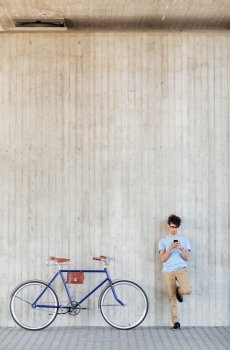 people, communication, technology, leisure and lifestyle - hipster man with smartphone and fixed gear bike on city street