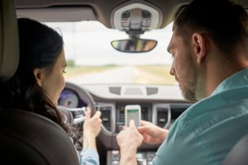road trip, travel, destination technology and people concept - happy man and woman with navigator on smartphone driving in car