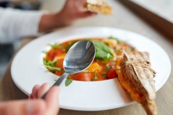 food, dinner, culinary and people concept - woman eating gazpacho soup with sandwich and spoon at restaurant