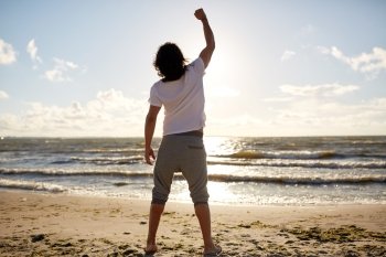 people, success, achievement and power concept - man with rised fist on beach
