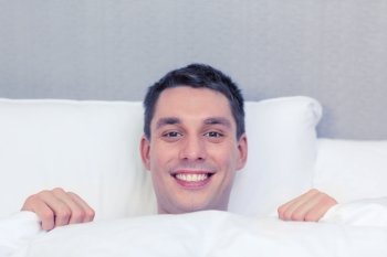 hotel, travel, relationships, and happiness concept - handsome man in bed