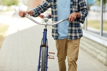 people, style and lifestyle concept - close up of young man with fixed gear bicycle walking along city street