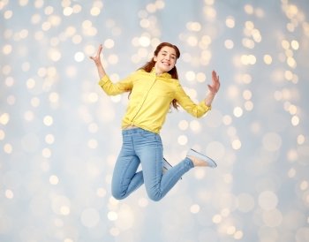 happiness, freedom, motion and people concept - smiling young woman jumping in air over holidays lights background