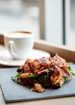 food, dinner, haute cuisine and eating concept - prosciutto ham salad on stone plate and coffee cup at restaurant