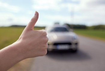 road trip, travel, gesture and people concept - hitchhiker stopping car with thumbs up hand sign