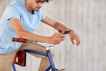 people, communication, technology, leisure and lifestyle - hipster man texting on smartphone with fixed gear bike on street
