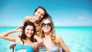 summer holidays, travel, people and vacation concept - happy young women in bikinis and shades over sea beach background