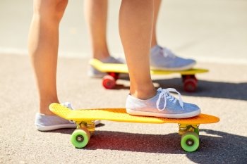 skateboarding, leisure, extreme sport and people concept - close up of young woman legs riding short modern cruiser skateboard on road