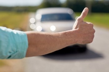 road trip, travel, gesture and people concept - man hitchhiking and stopping car with thumbs up gesture at countryside