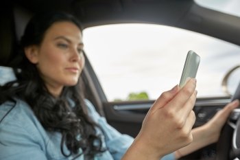 road trip, technology, travel and people concept - happy woman driving car with smarhphone