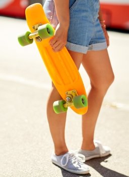 summer, extreme sport and people concept - teenage girl with short modern cruiser skateboard on city street