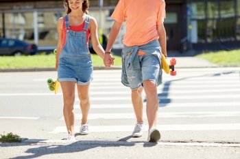 summer holidays, extreme sport, relations and people concept - happy teenage couple with short modern cruiser skateboards crossing city crosswalk
