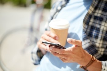 leisure, technology, communication and people concept - close up of man with smartphone and coffee cup texting message on city street