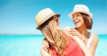 summer holidays, travel, people and vacation concept - happy young women in hats over exotic tropical beach background