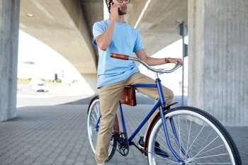 people, communication, technology, leisure and lifestyle - hipster man with fixed gear bike calling on smartphone on street