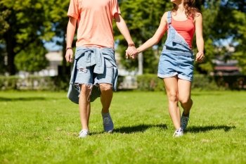 holidays, vacation, love and people concept - happy teenage couple walking in summer park