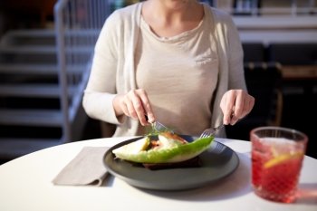 food, new nordic cuisine and people concept - woman eating toast skagen with shrimps, lemon mayonnaise, caviar and buttery bread with fork and knife at cafe or restaurant