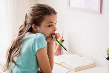people, children, education and learning concept - bored girl with book and pen doing homework at home