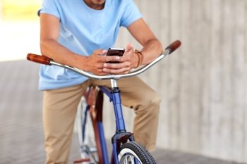people, communication, technology, leisure and lifestyle - close up of man texting on smartphone with fixed gear bike on city street