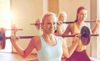 fitness, sport, training and lifestyle concept - group of happy women with barbells exercising in gym. group of women with barbells exercising in gym