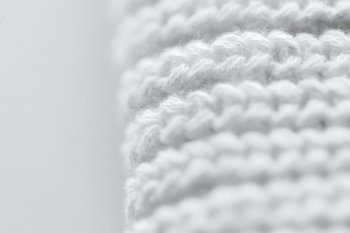 handicraft, knitwear and needlework concept - close up of white knitted item